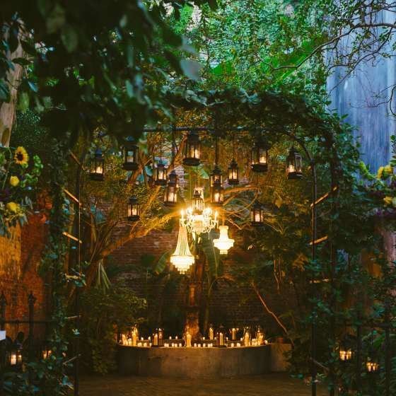 Venue with hanging light fixtures, lots of natural greenery and candlelight.